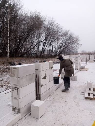 Нанесение клеевого раствора на блок газобетона перед укладкой