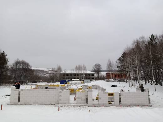 Рабочие на верху газобетонных стен зимой