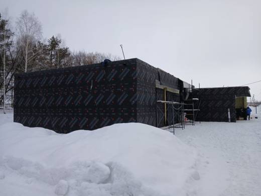 Дом обёрнут ветрозащитной мембраной зимой